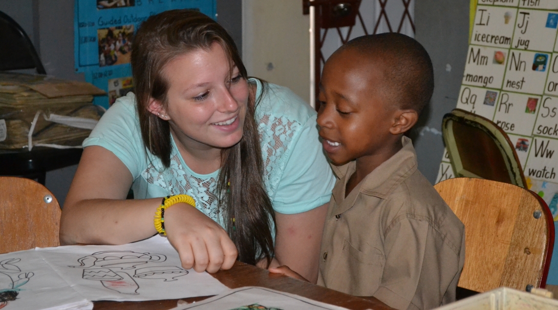 A Projects Abroad volunteer works closely with children in Jamaica with a group. A volunteer goes through an English exercise during childcare volunteering in Jamaica for groups.